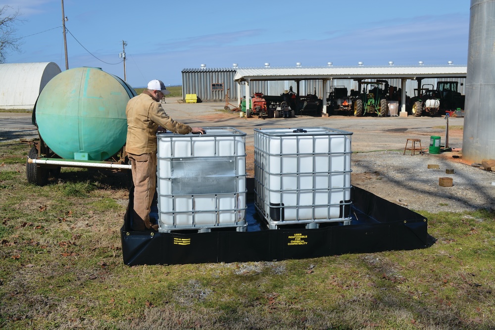 Two white plastic IBC totes on an Angle Bracket spill containment berm