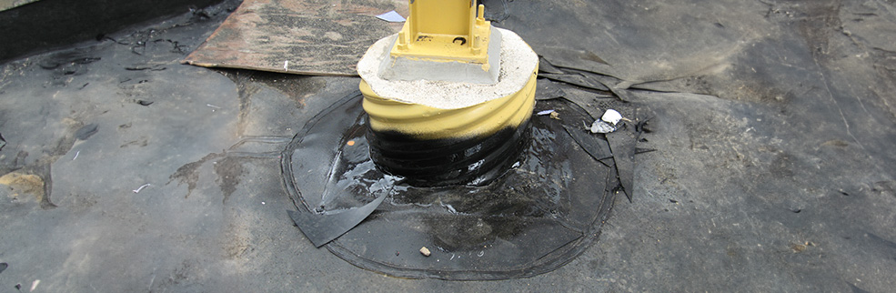 A close-up of a yellow support column base sealed with a containment liner system, on a textured surface.